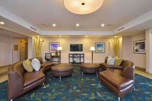 A hotel lobby with leather sofas, a round coffee table, and a flat-screen TV on the wall. - Candlewood Suites Harrisburg - Hershey by IHG (Harrisburg)