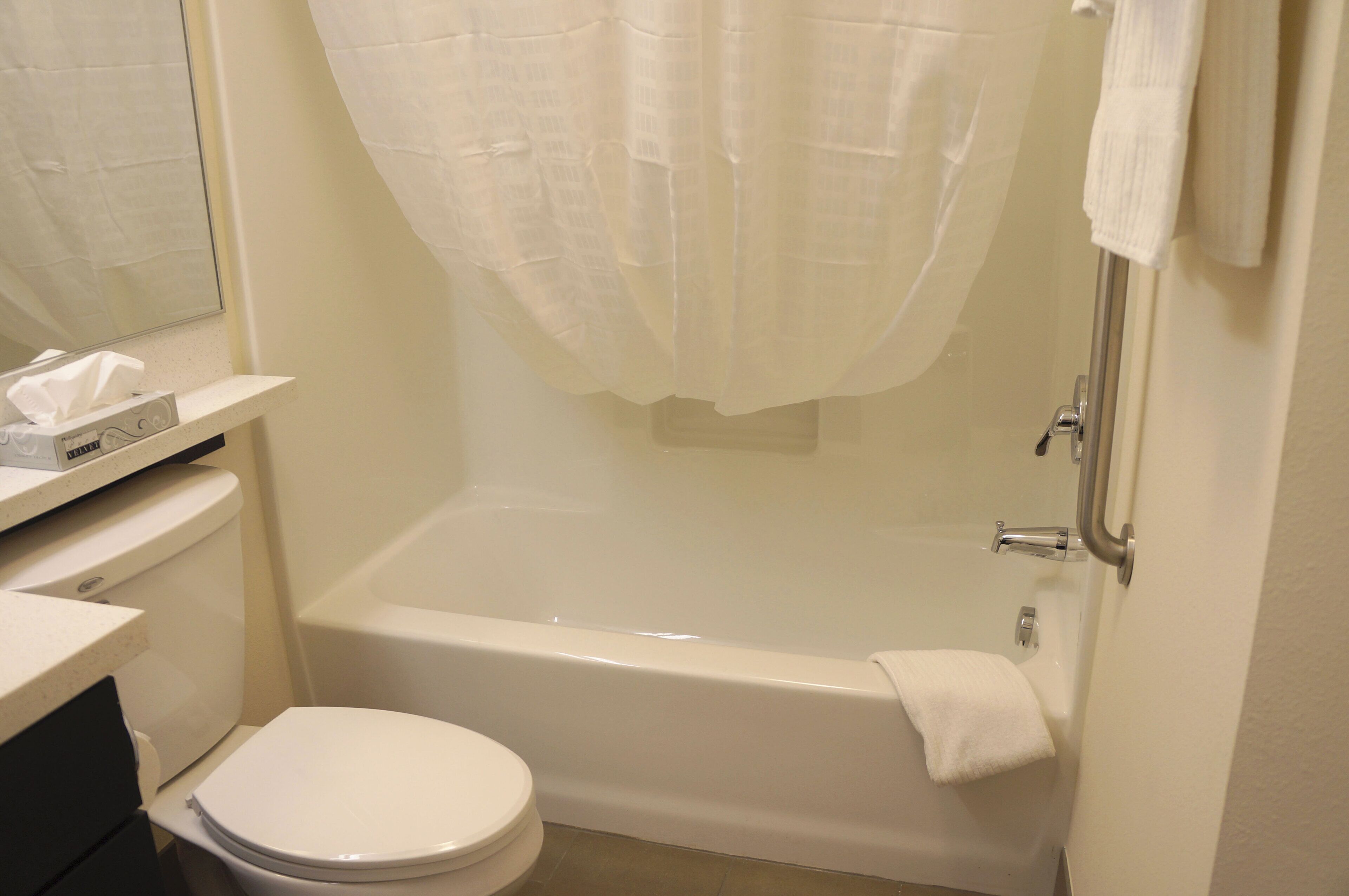 Et badeværelse med et hvidt badekar, toilet og vask.