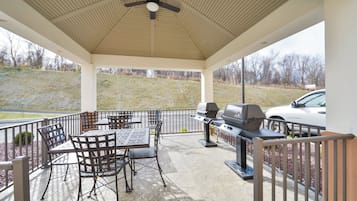 A covered patio area with a ceiling fan, outdoor seating, and a grill.