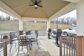 A covered patio area with a ceiling fan, outdoor seating, and a grill.