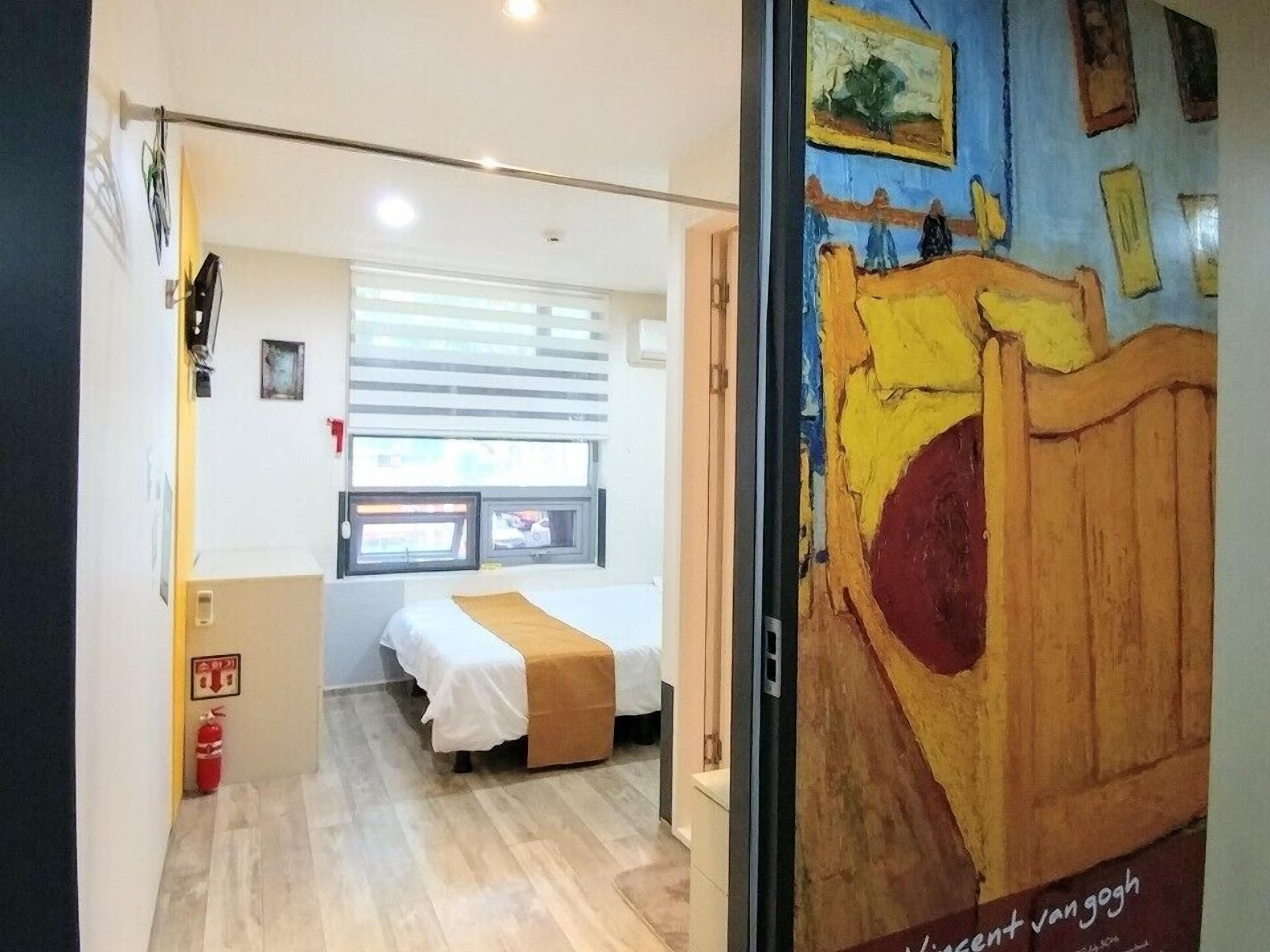 A room with a bed, a window, and a door leading to another room.
