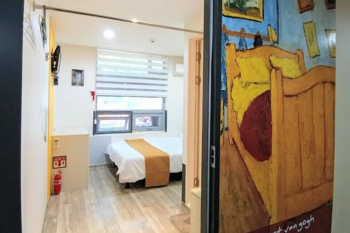 A room with a bed, a window, and a door leading to another room.