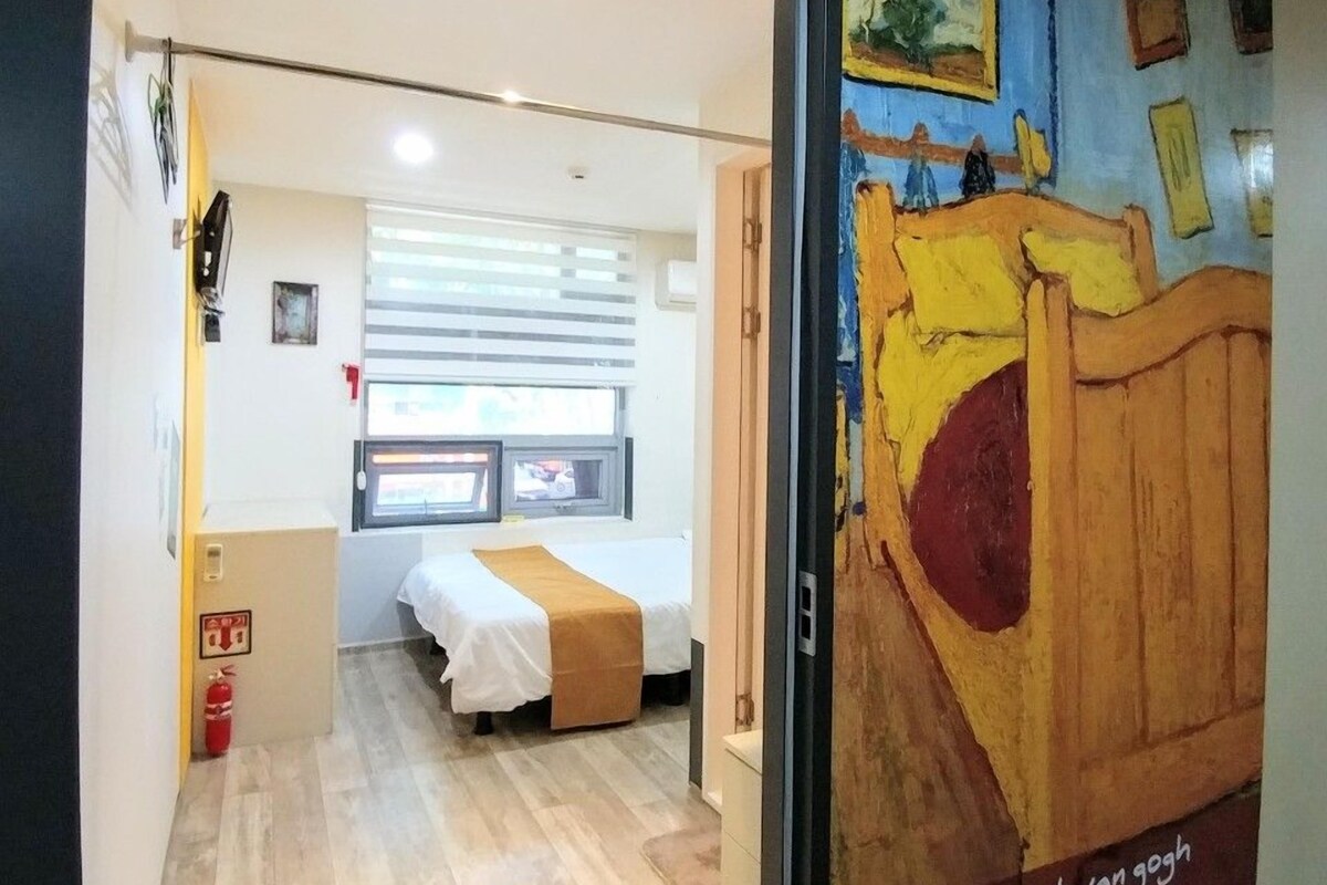 A room with a bed, a window, and a door leading to another room.