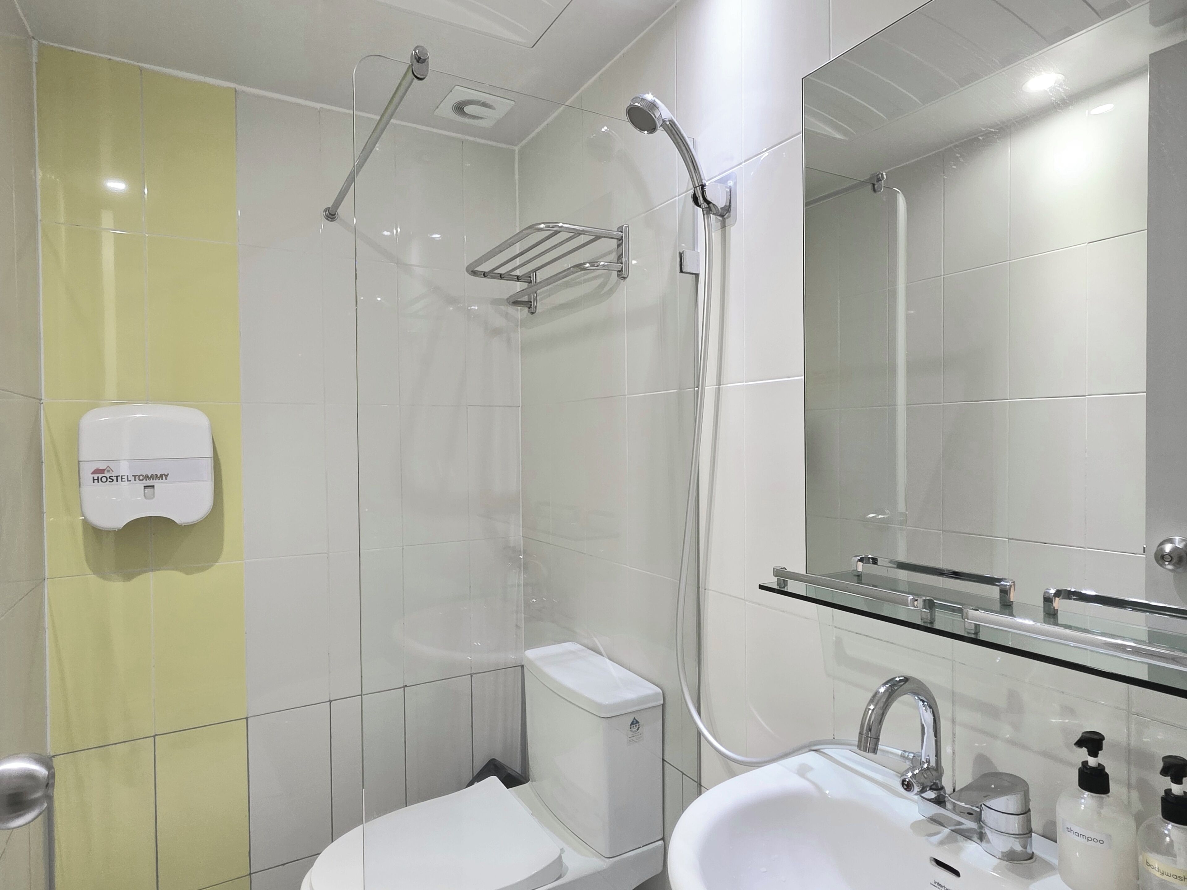 A modern bathroom with a glass shower enclosure, a toilet, a sink with a mirror, and toiletries.