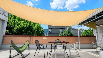 An outdoor patio with a table, chairs, a hammock, and a shade sail.