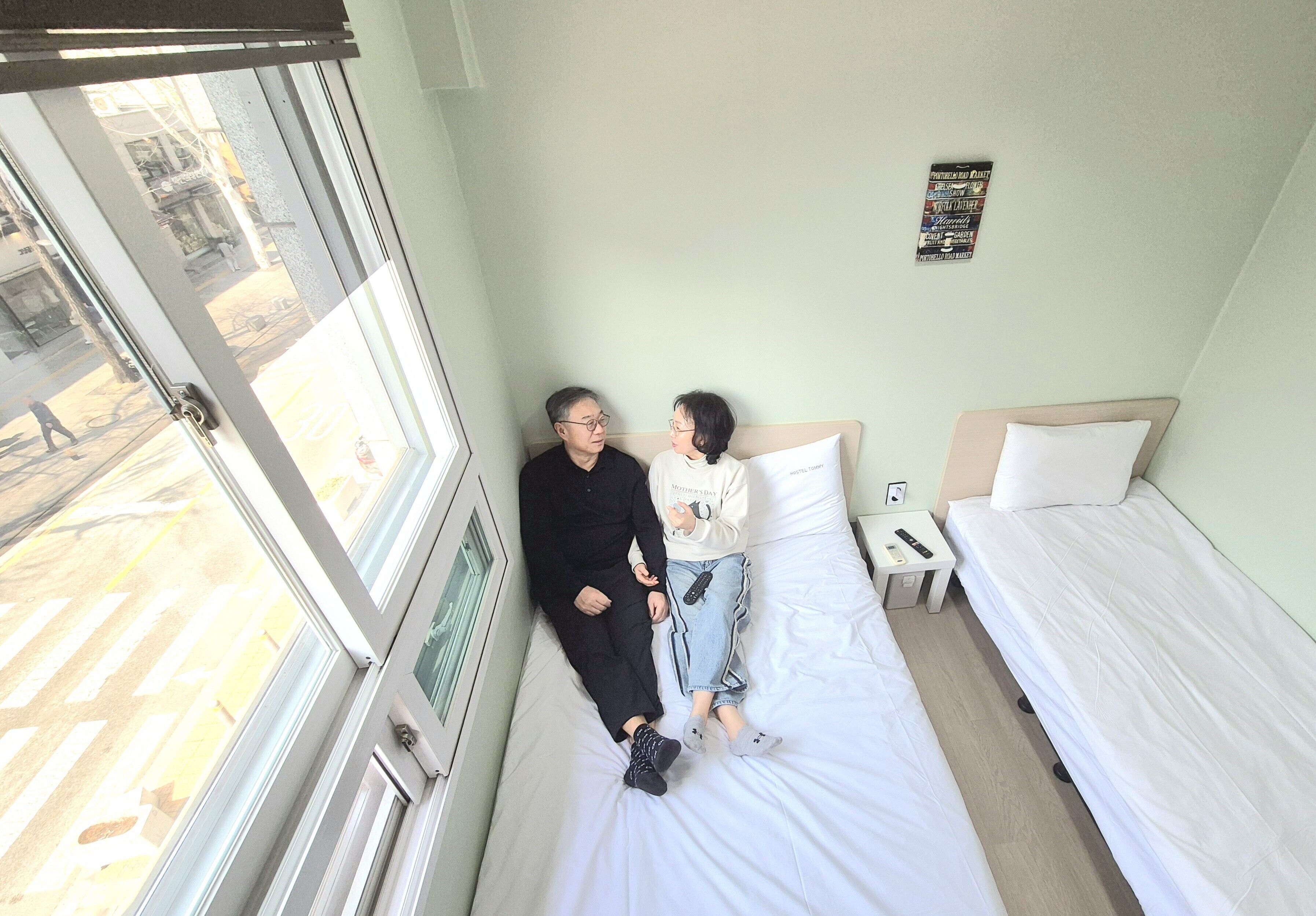 Una habitación con dos camas, una ventana y una pared con un cartel.