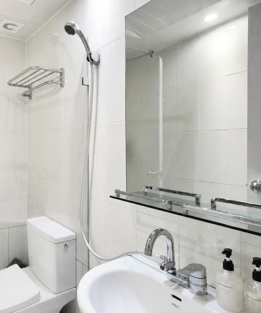 A modern bathroom with a glass shelf, a toilet, a sink, and a shower.