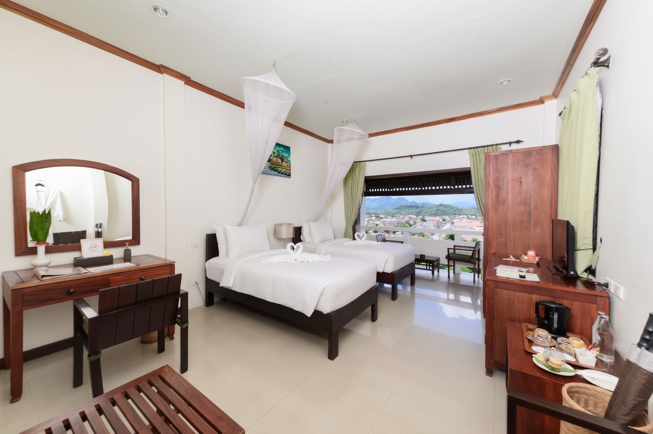 A hotel room with a bed, a desk, a chair, a TV, and a view of the city.