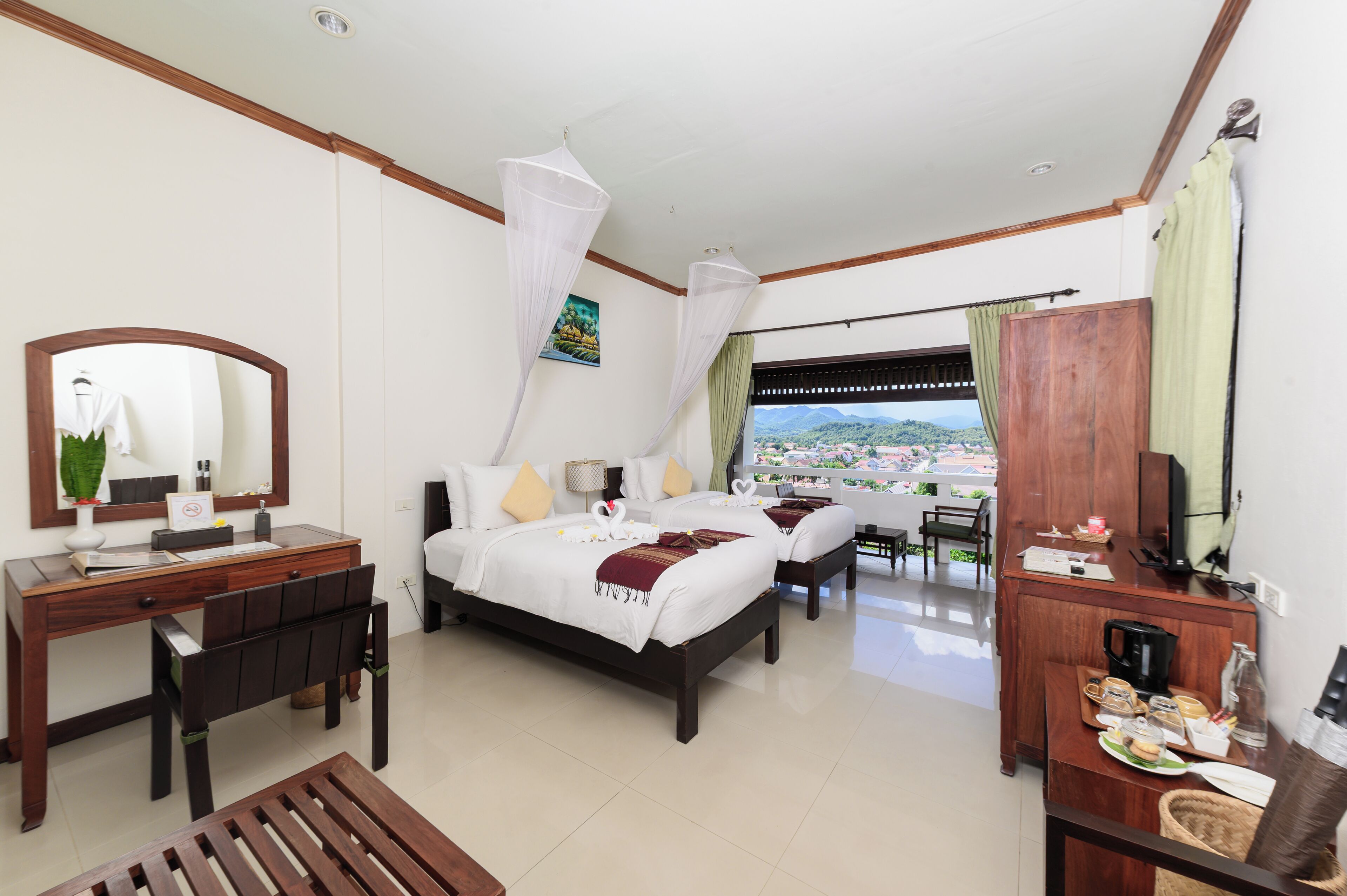 A hotel room with a bed, desk, and a view of a cityscape.