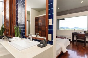 Un baño moderno con un espejo grande, un lavabo y una ducha. Hay una ventana con vistas a montañas.