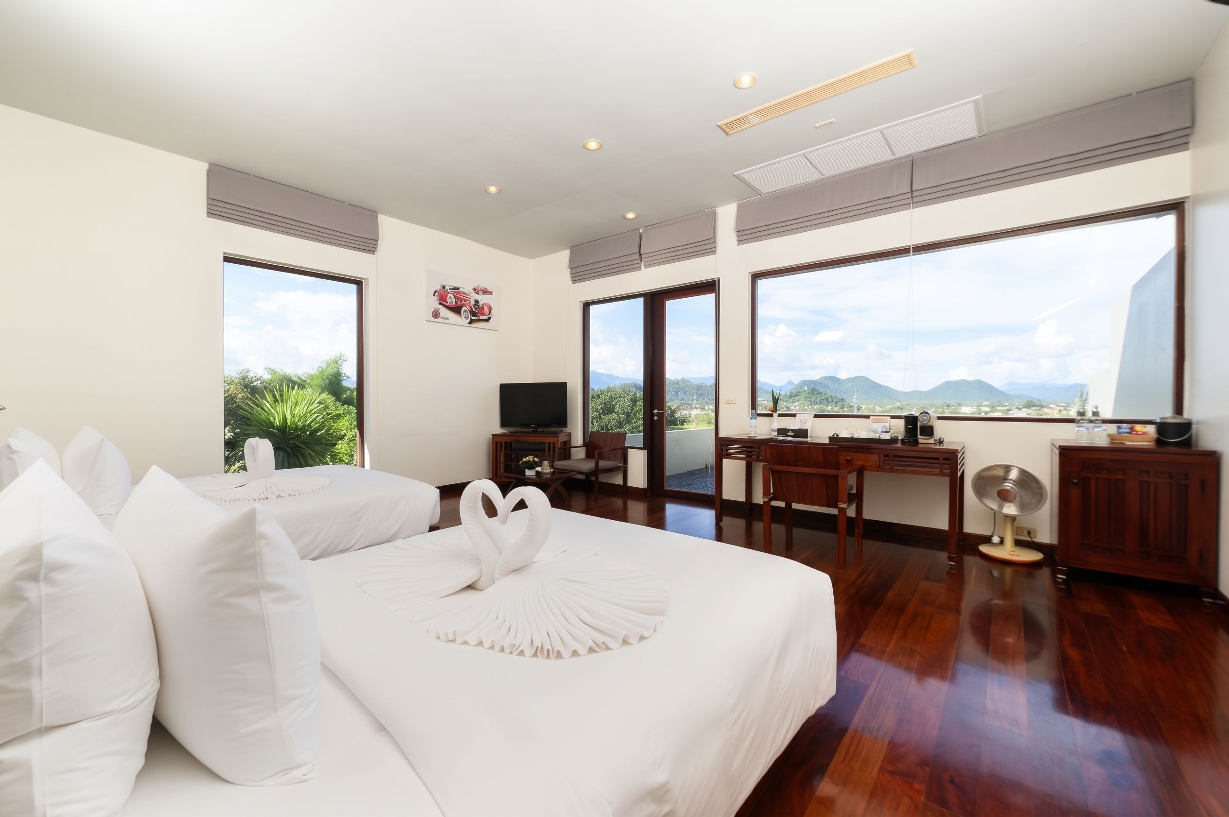 Habitación de hotel con una cama grande, un escritorio, una silla, un televisor y vistas a la montaña.