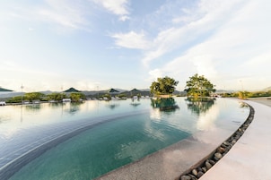 Una piscina al aire libre, sombrillas, sillones reclinables de piscina