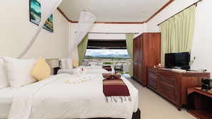 Una habitación de hotel con cama, escritorio, televisor y vista al paisaje.