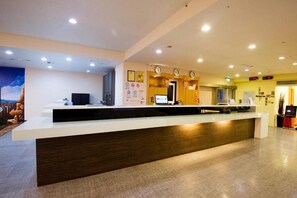 A reception desk with a computer, a clock, and a wall with various signs. - Ximen Holiday Fun Hotel (Taipei)