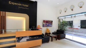 A hotel reception area with a reception desk, seating, a TV, and clocks on the wall. - Especen Hotel (Hanoi)