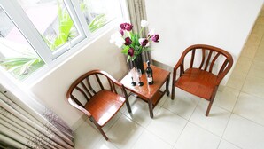 A dining area with a table, two chairs, a vase with flowers, and a bottle. - Especen Hotel (Hanoi)