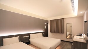 Quarto de hotel com duas camas, uma escrivaninha, um espelho e um banheiro.