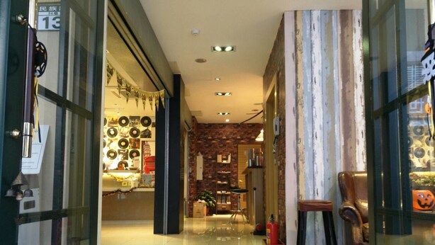 A hotel lobby with a modern design, featuring a brick wall, a fireplace, and a seating area with leather chairs. - Golden Hotel (New Taipei City)