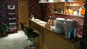 A kitchen with a brick wall, a wooden counter, and a black chair. - Golden Hotel (New Taipei City)