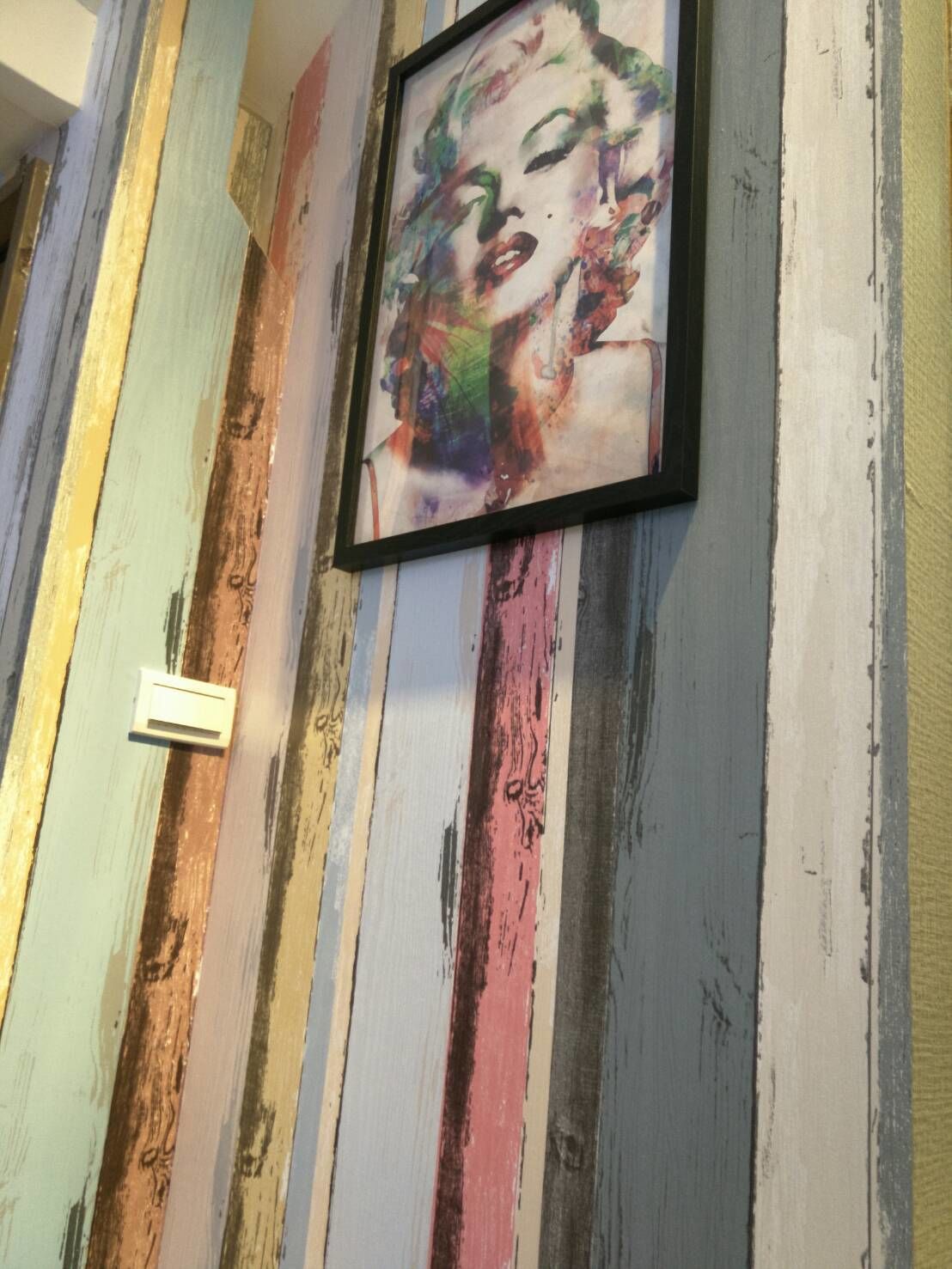A wall with a colorful, distressed paint finish and a framed artwork.