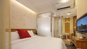 A hotel room with a large bed, a desk, a TV, and a shower area. - Golden Hotel (New Taipei City)
