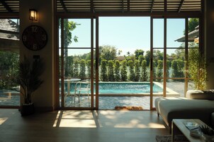 Habitación con una ventana grande que da a una piscina, un sofá y un reloj en la pared.