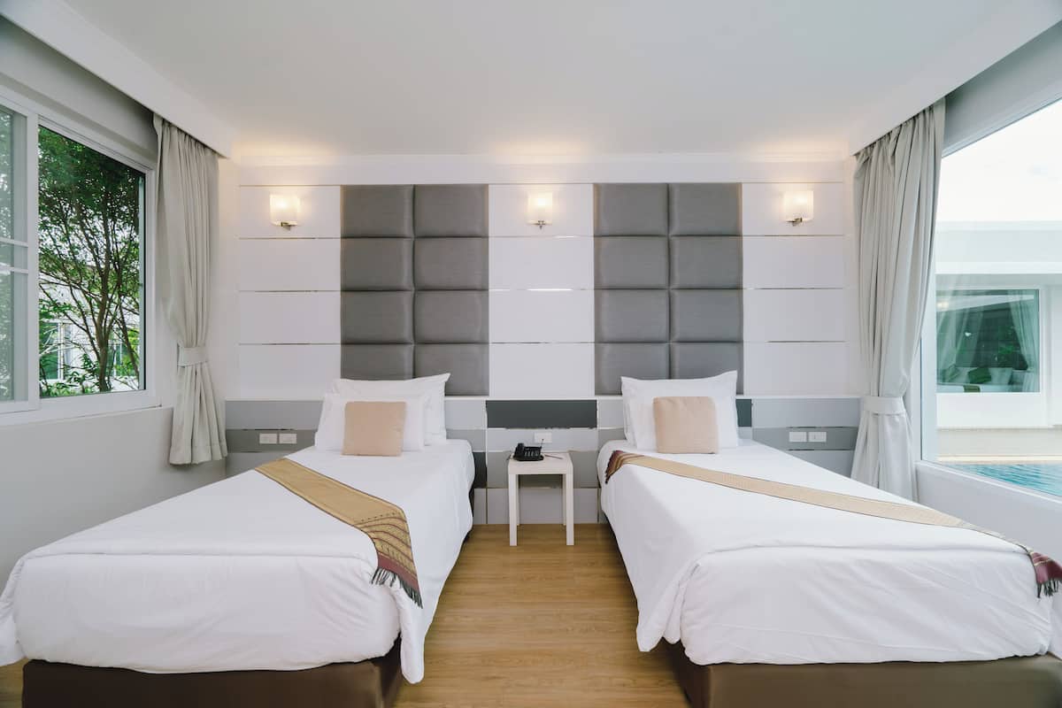 Ein modernes Hotelzimmer mit zwei Betten, einem kleinen Tisch und Blick ins Freie.