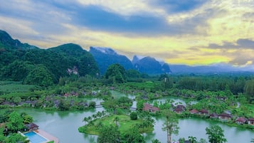 Een resort met meerdere bungalows, omgeven door weelderige begroeiing en een meer.