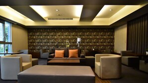 A modern hotel room with a large bed, multiple seating areas, a bookshelf wall, and a large window. - SLV Hotel Group - SLV Business Hotel (New Taipei City)