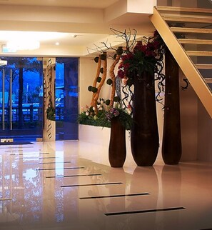 A modern lobby with a reflective floor, a staircase, and decorative vases with flowers. - SLV Hotel Group - SLV Business Hotel (New Taipei City)