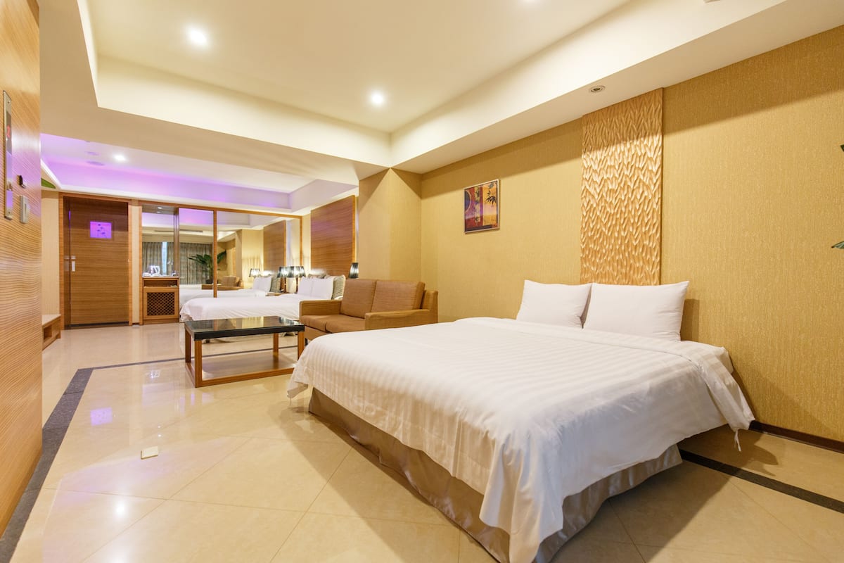 A modern hotel room with a large bed, a seating area, and a mirror.