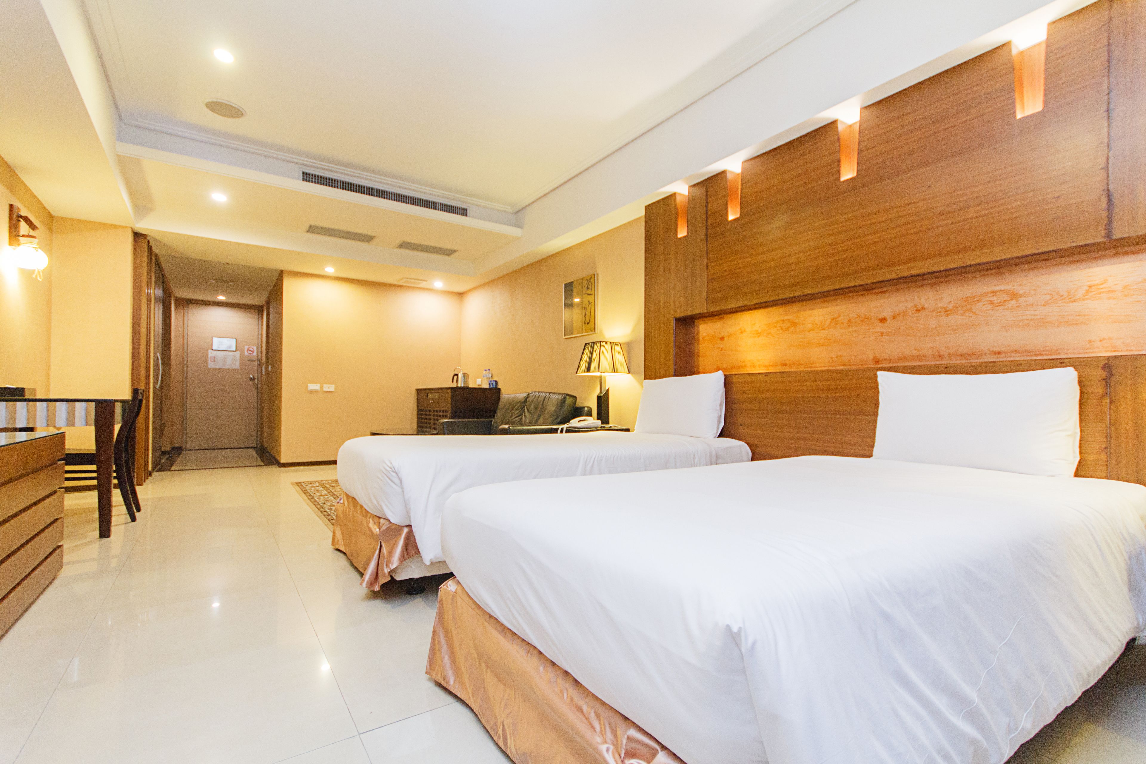 A hotel room with two beds, a desk, and a chair.