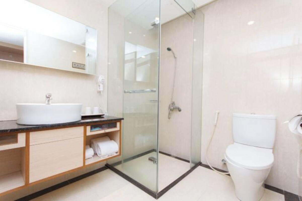 A modern bathroom with a glass-enclosed shower, a white sink, and a toilet.