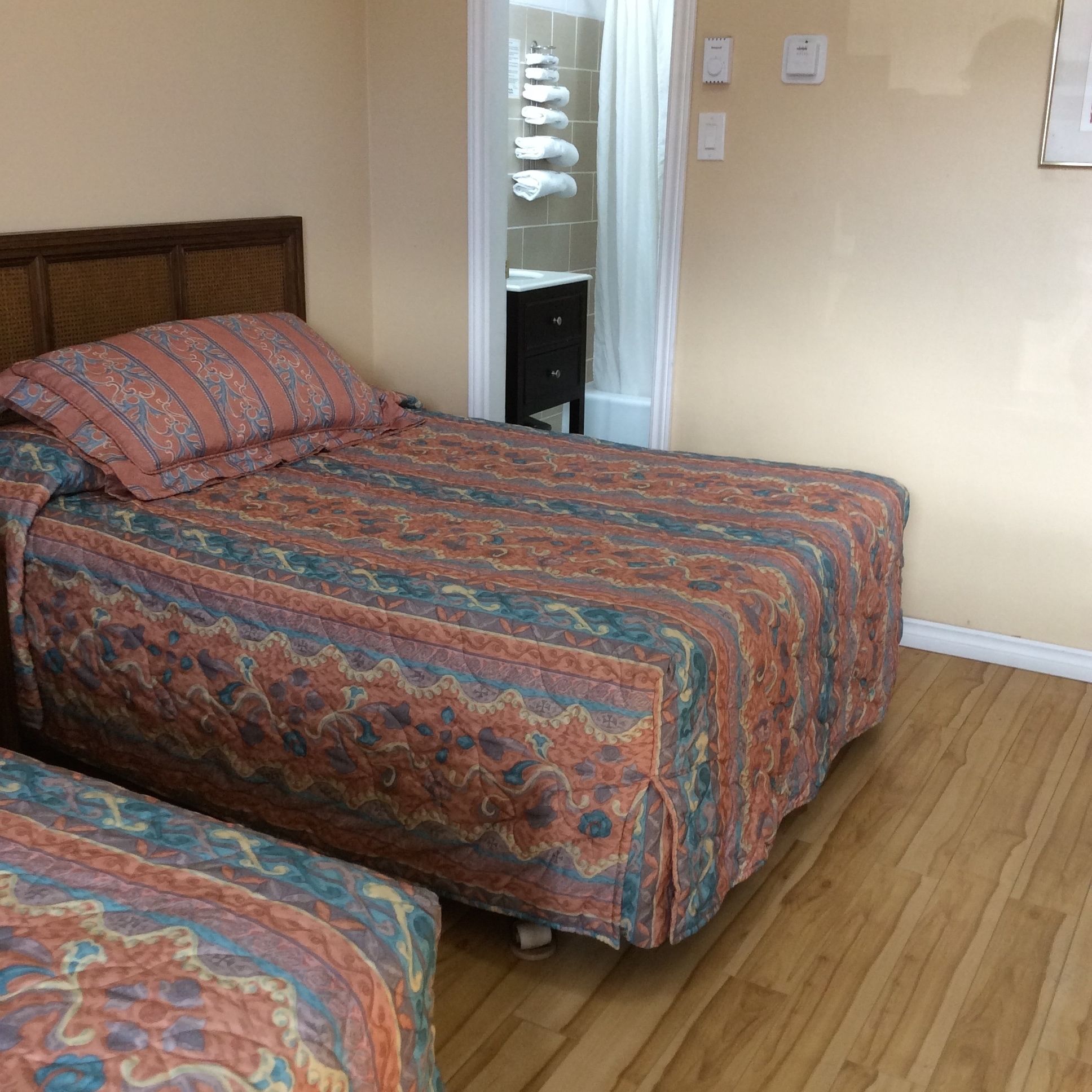 Une chambre à coucher avec un lit, une table de chevet et une armoire où sont suspendus des vêtements.