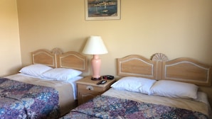 A hotel room with two beds, each with a wooden headboard, a nightstand with a lamp, and a painting on the wall. - Lion Motel (South Stormont)