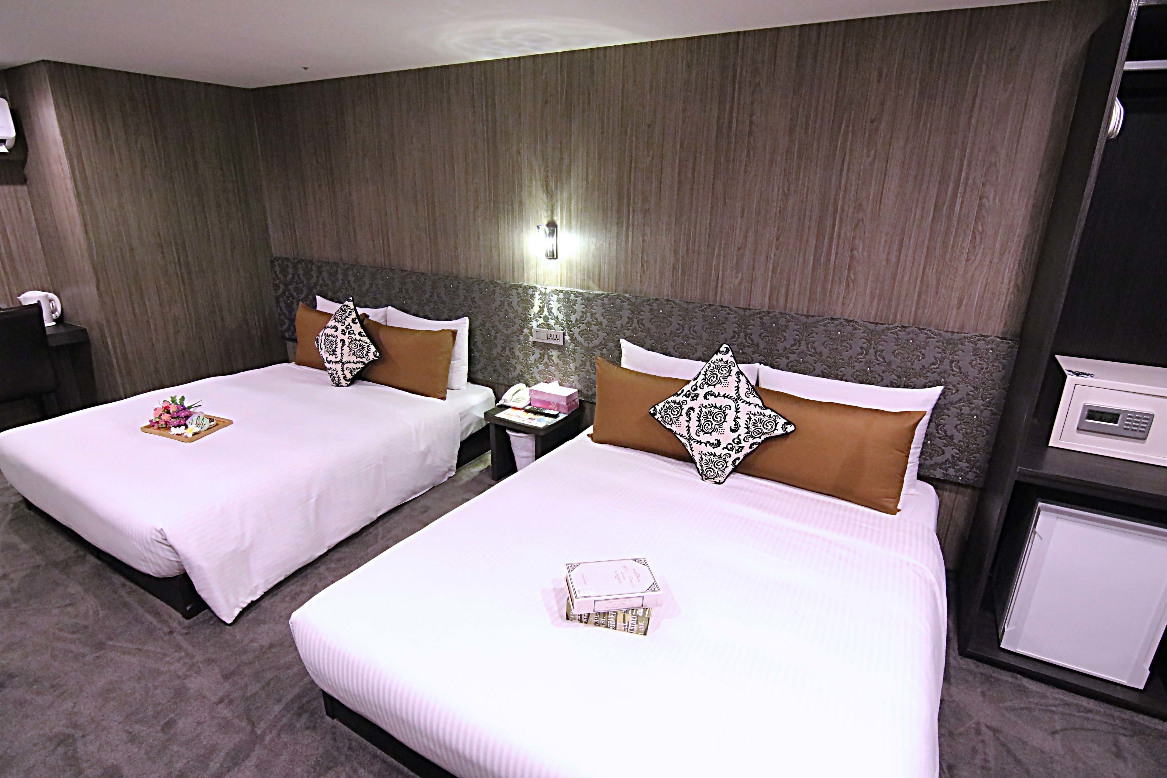 Habitació d'hotel amb dos llits, cadascun amb un coixí i un cistell amb flors. Hi ha una tauleta de nit amb un telèfon i una làmpada.