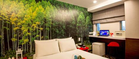 Habitación de hotel con una cama, un escritorio con computadora, una silla roja y una pared con un mural de un bosque.