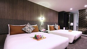 A hotel room with two beds, each with a wooden headboard, a nightstand, and a tray with flowers. - Hotel 6 - Wannien (Taipei)