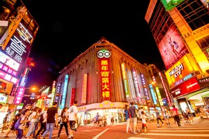 A brightly lit building with large signage and a crowd of people in front. - Hotel 6 - Wannien (Taipei)