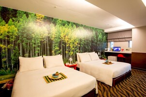 Een hotelkamer met twee bedden, een bureau en een grote wanddecoratie van een bos.