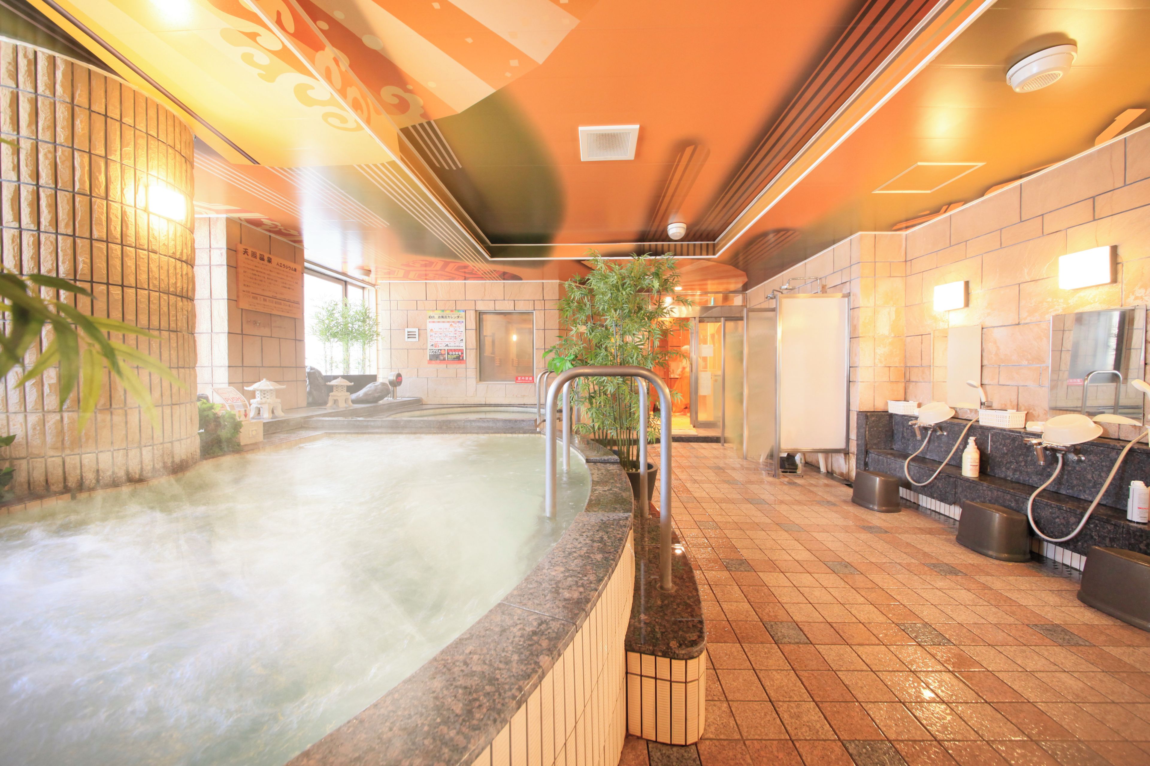 A hot spring area with a tiled floor, a hot tub, and a seating area with a plant.