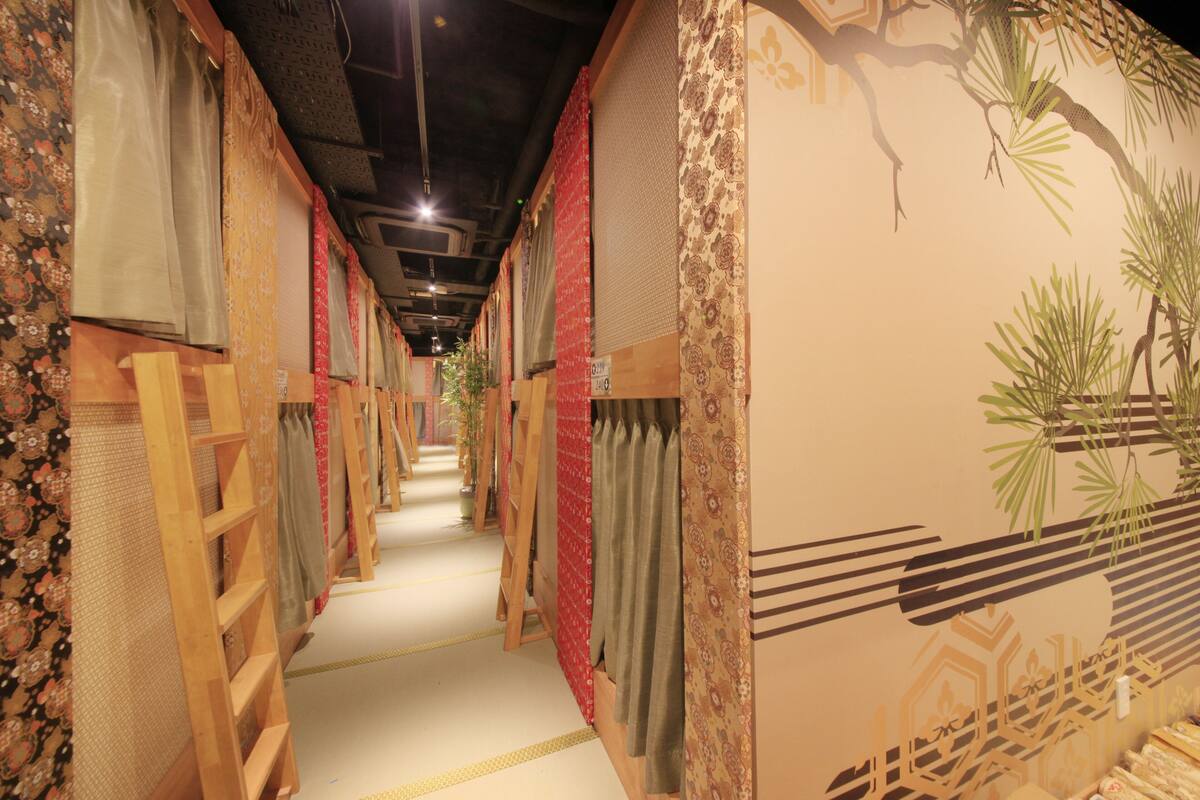 A corridor with wooden bunk beds and patterned curtains.