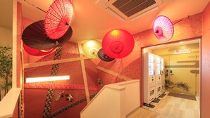 A hotel lobby with a staircase, decorative umbrellas, and a reception area.