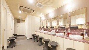 A hotel bathroom with multiple sinks, mirrors, and stools.