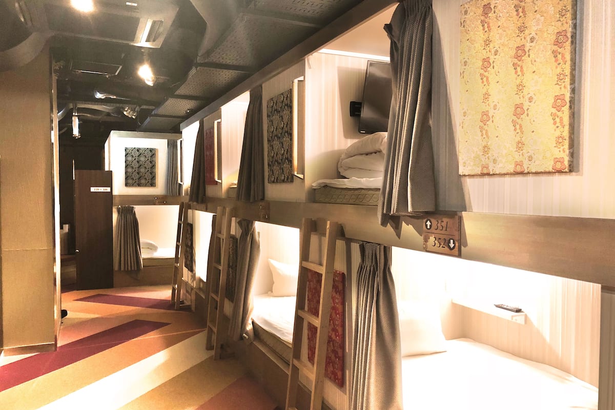 A train compartment with bunk beds, a television, and a small table.