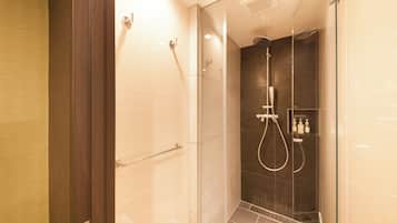 A glass-enclosed shower stall with a handheld showerhead and a wall-mounted faucet.
