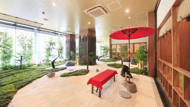 A serene indoor garden with a red table, rocks, and a wooden bench. - Ueno Station Hostel Oriental 1 - Caters to Men (Tokyo)