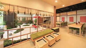 A spacious indoor area with a traditional Japanese garden, wooden tables, and benches. - Ueno Station Hostel Oriental 1 - Caters to Men (Tokyo)