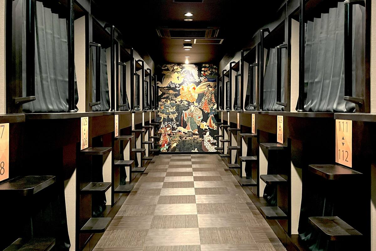 A hotel corridor with checkered flooring, rows of seating, and a mural on the wall.