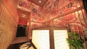 A corridor with a patterned wall, a reception desk, and a potted plant. - Ueno Station Hostel Oriental 1 - Caters to Men (Tokyo)
